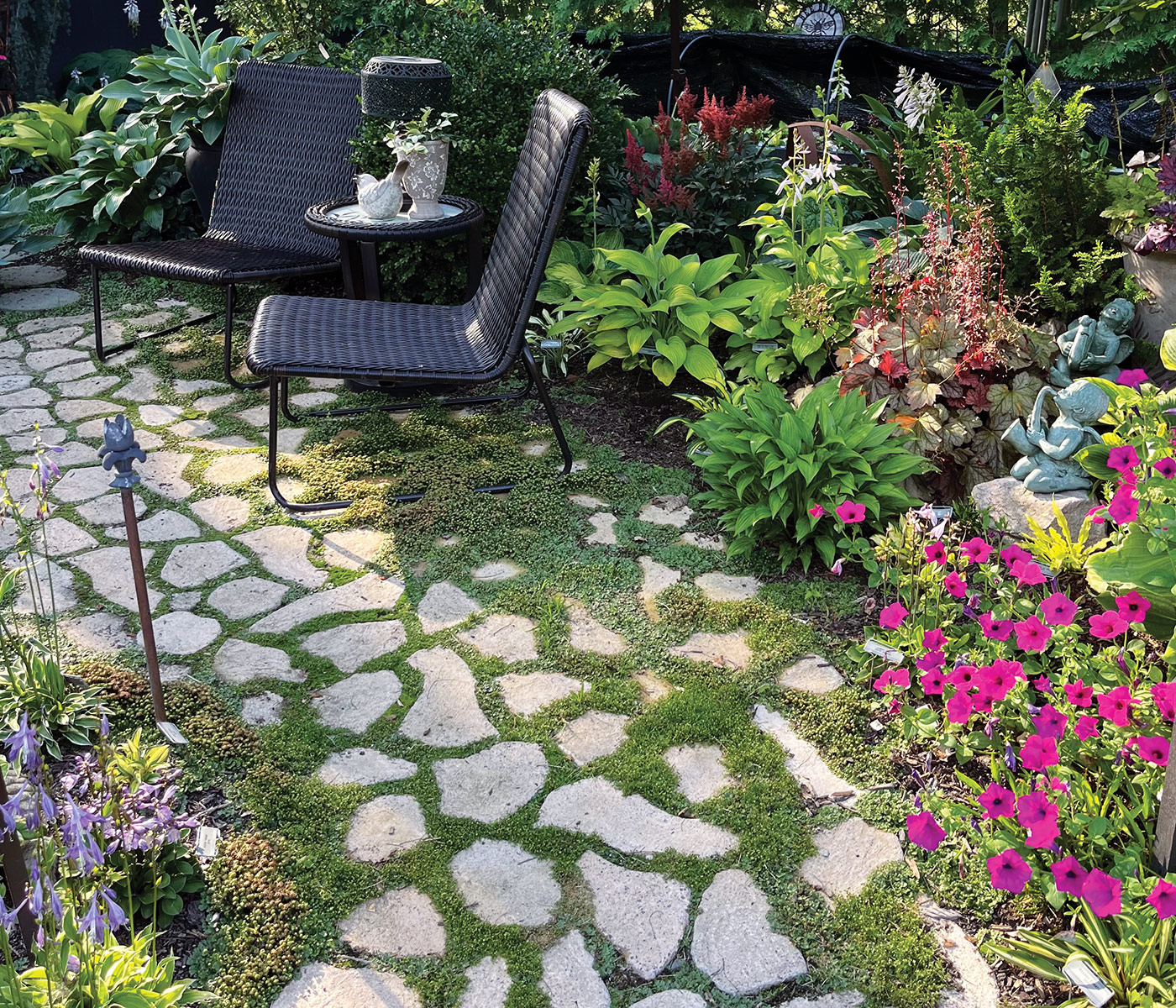 Lonna Engel patio: A charming stone patio is surrounded by a mix of hostas and cheery pink petunias.