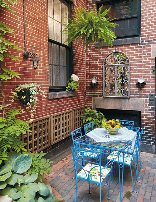 Blue patio furniture in urban courtyard with mirror: A wrought-iron patio set, wall sconces and a decorative mirror add style to this small space.