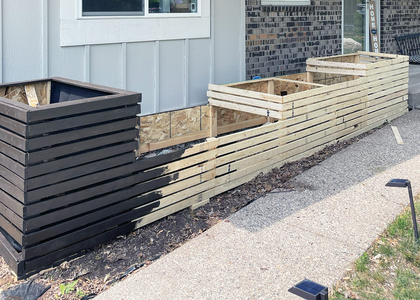 Raised bed DIY progress shot: A brown stain coordinates with the brick siding and ensures the plants take center stage. Photo courtesy of Ryan McEnaney 