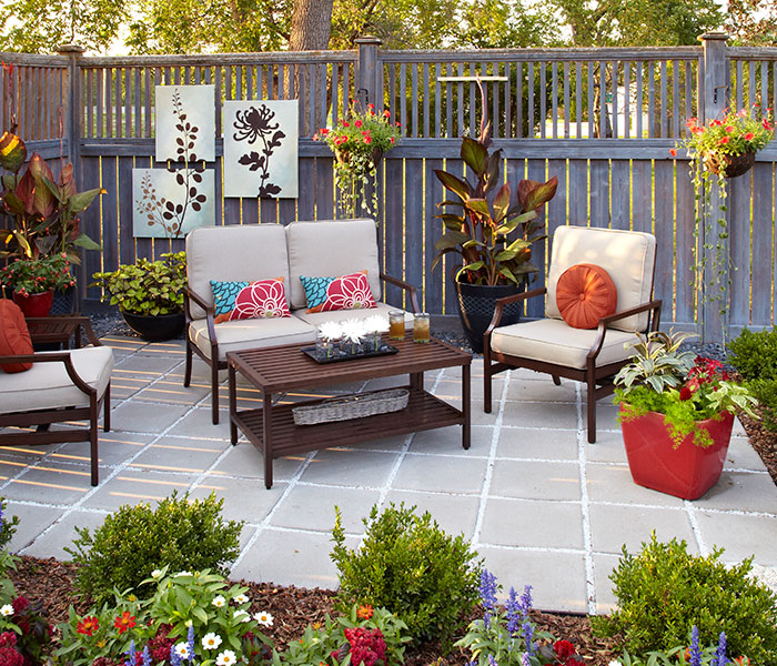 Finished paver patio with furniture and plants: A new DIY patio, a few colorful annuals and some fresh garde decor transformed this unused corner into a relaxing and inviting getaway.