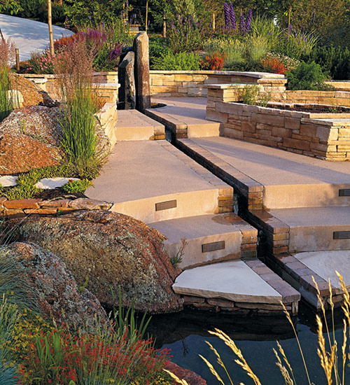 low maintenance plants around unique fountain: Enjoy the sound of water both outside and indoors. The sound of falling water close to the house lets you enjoy the natural surroundings through an open window.