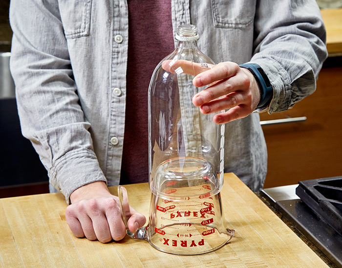 soda-bottle-cloche-harden-ring-on-pyrex-measuring-cup: Quickly remove the bottle from the skillet and place it over the bottom of an inverted, 2-cup glass measuring cup to form a perfect ring as the plastic cools.