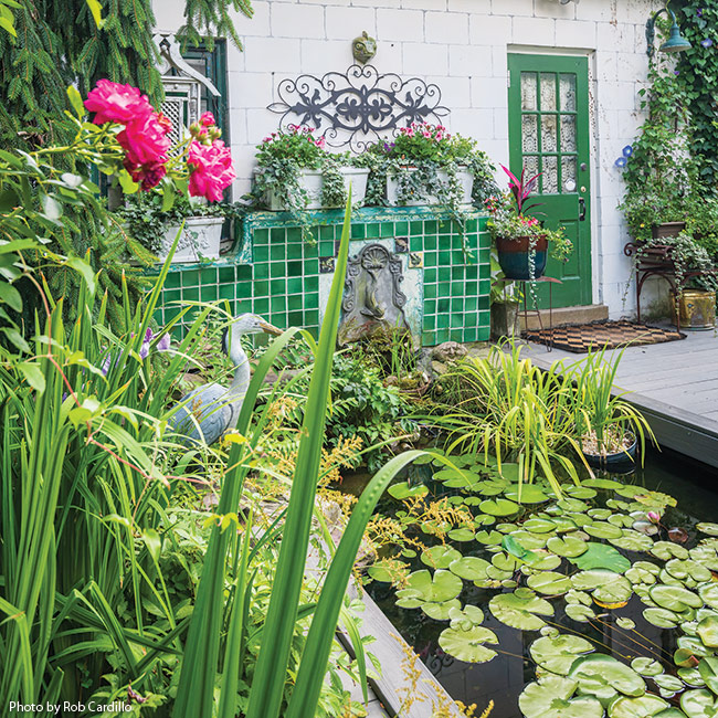 pond with huron statue: The figure of a great blue heron stands guard over the water lilies (Nymphaea spp.), lotus (Nelumbo spp.) and containers of yellow flag iris (Iris pseudacorus). 
