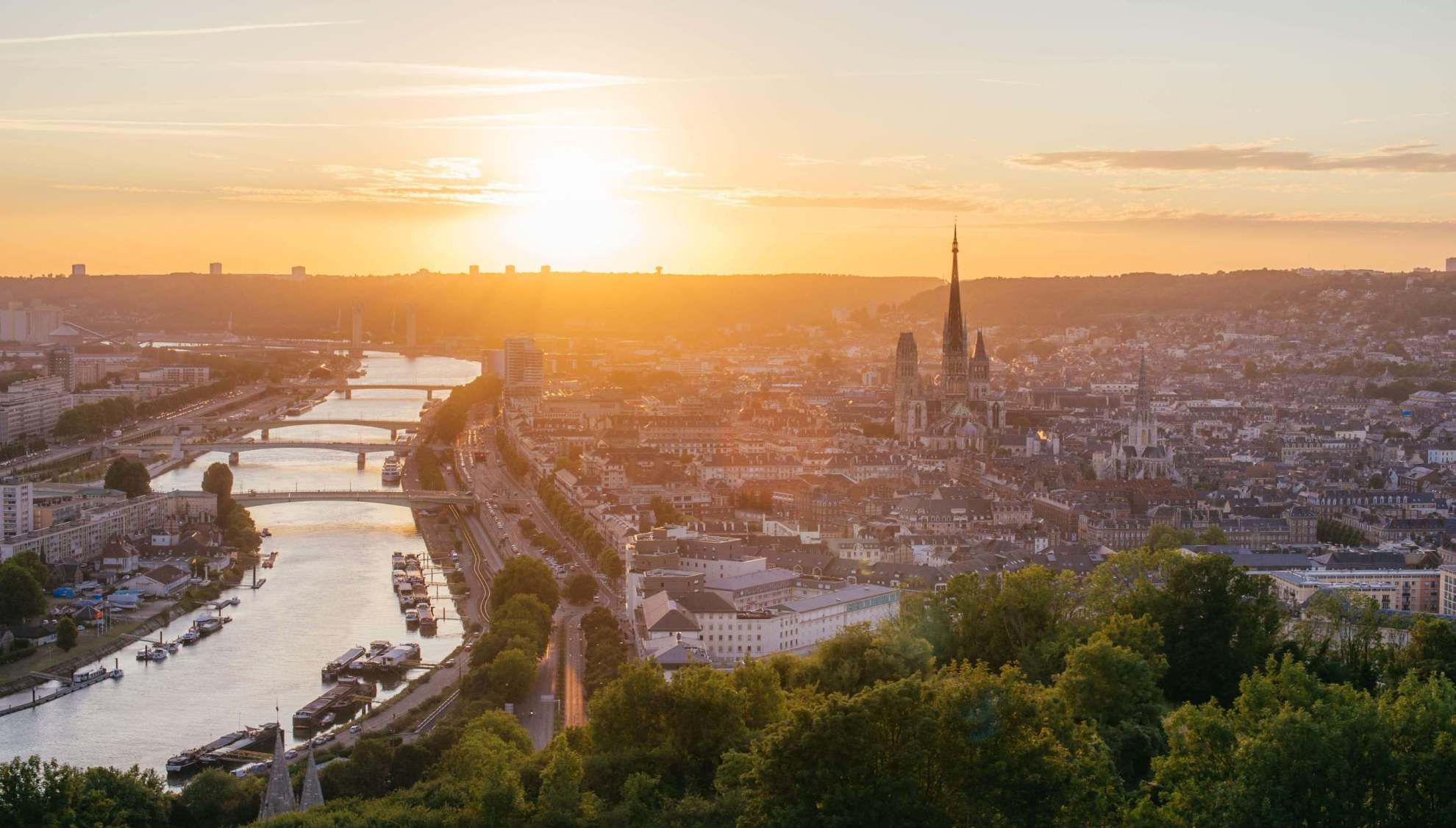 A view of Rouen at sunset with the silhouette of the cathedral overlooking the river Seine