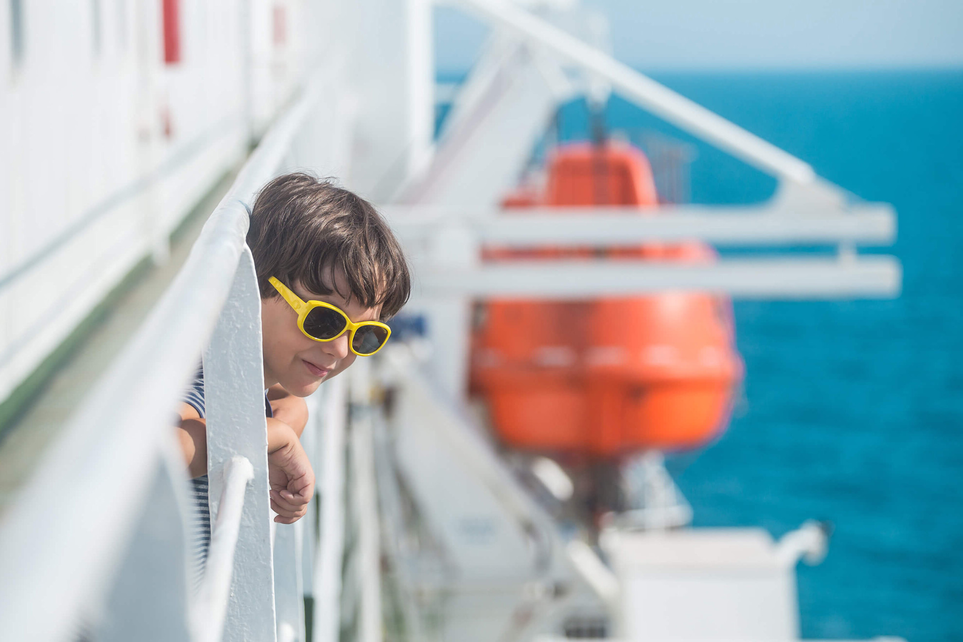 Un niño con gafas de sol en cubierta mirando al mar
