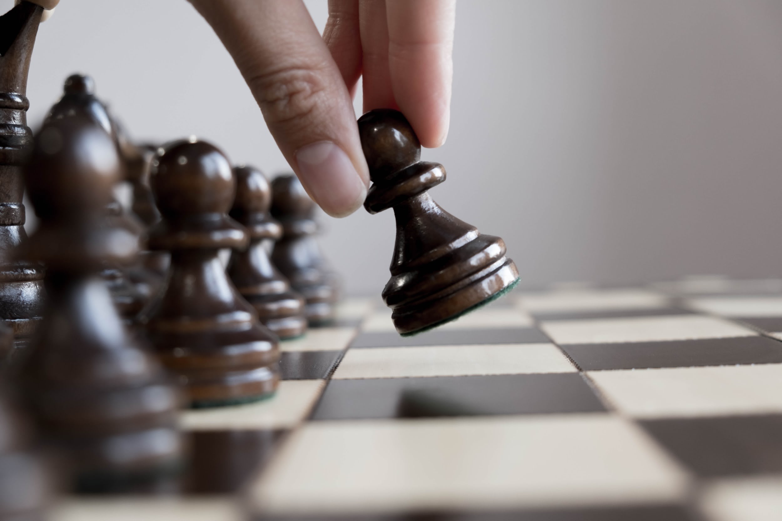 Image of a chessboard with a hand moving a pawn