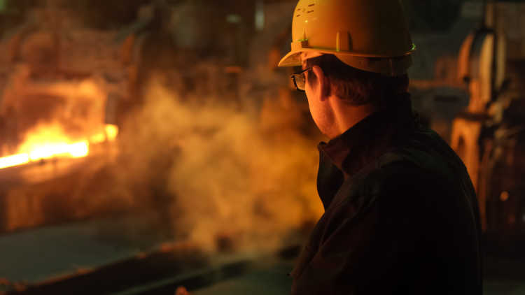 Man in hard hat looking at fire and smoke at night