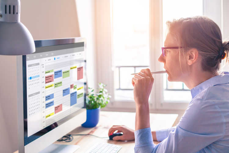 Woman in office looking at calendar on computer screen