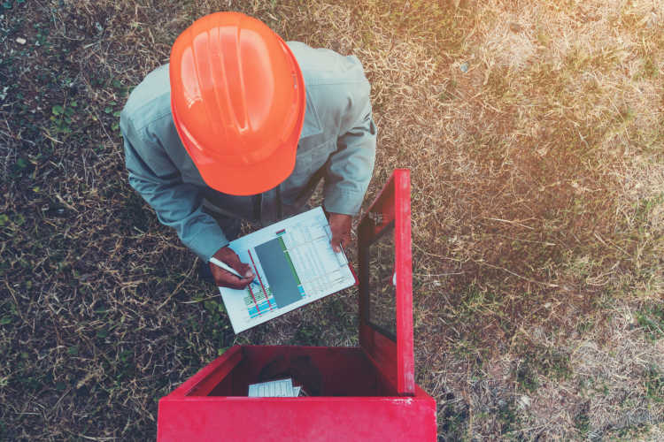 Birds eye view of man in hard hat outdoors with clipboard