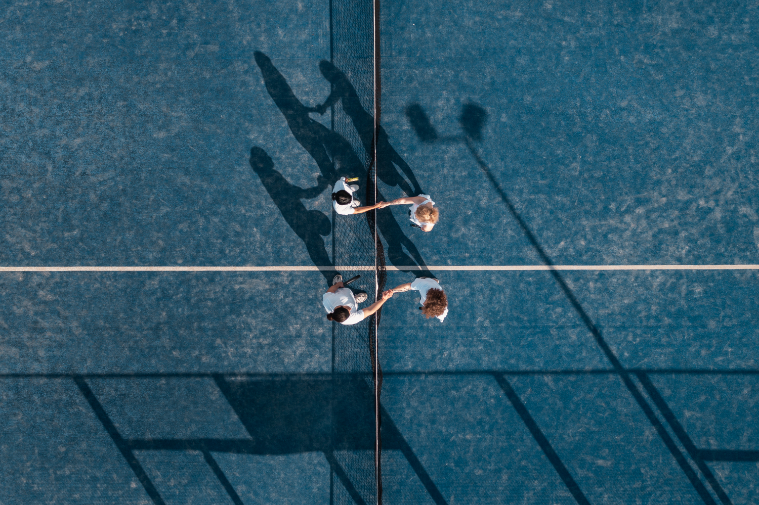 4 pickleball players shaking hands on the pickleball court