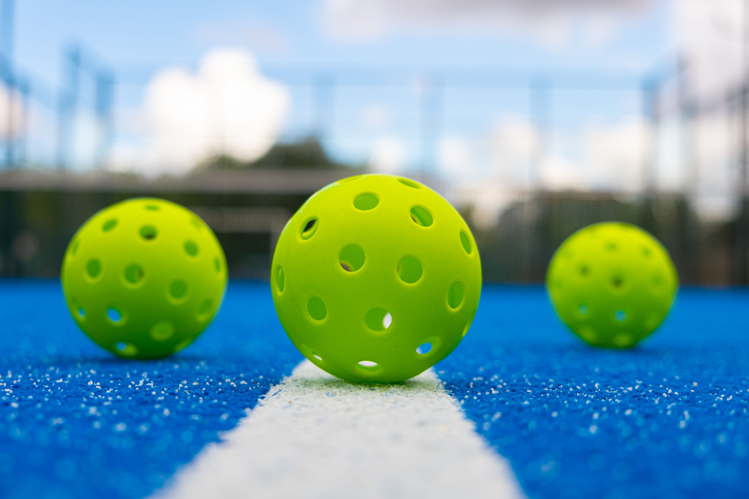3 green pickleball balls on the court