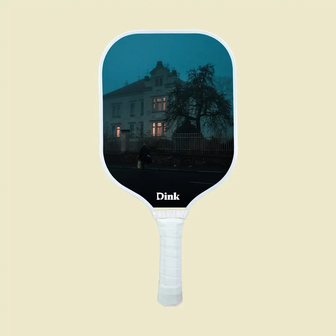 a pickleball paddle design with an old man in front of an old spooky house in the evening