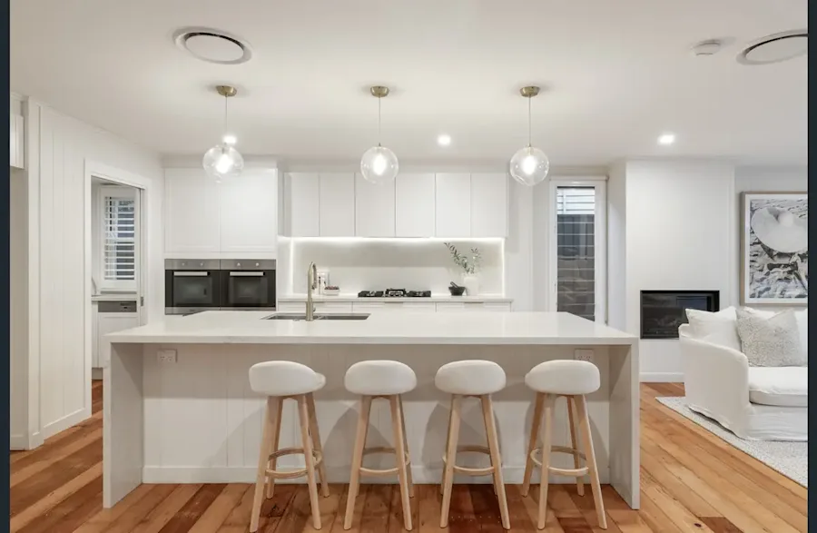 A modern kitchen and living space warmed by a whole-home ducted heat pump controlled by AirTouch 5