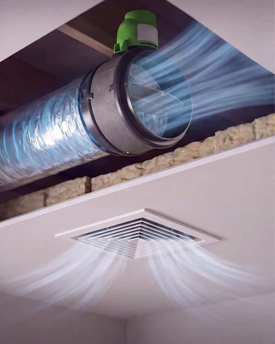Cutaway of a ceiling showing a green AirTouch zone damper opening a flexible duct so conditioned air flows out of the vent into the room below