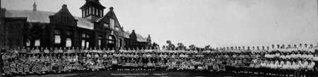 Rows of students standing in front of an old building.