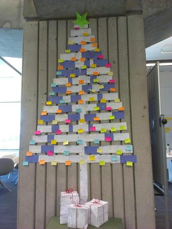 Christmas tree shape made from post it notes on a wall.