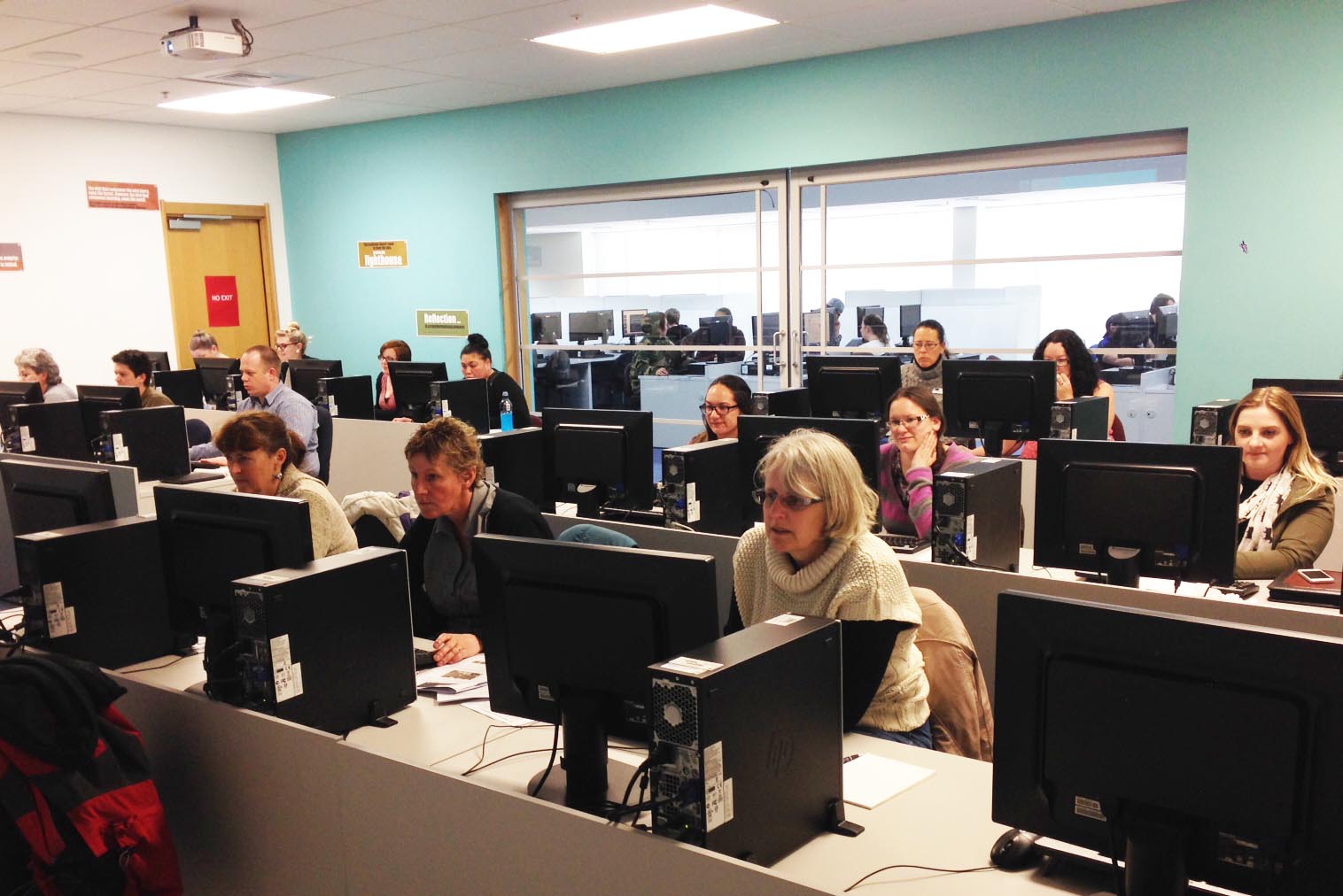 A group of people sitting in  rows at computers.