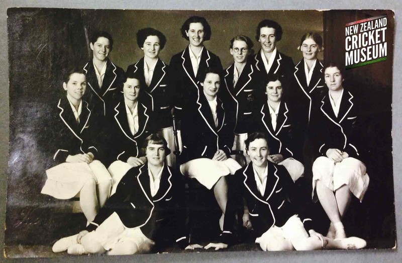 A team photo of 13 women wearing black blazers and white skirts.