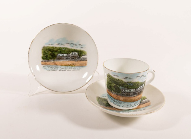 Tea cup and saucers with a colour illustration of a large building on the waterfront.