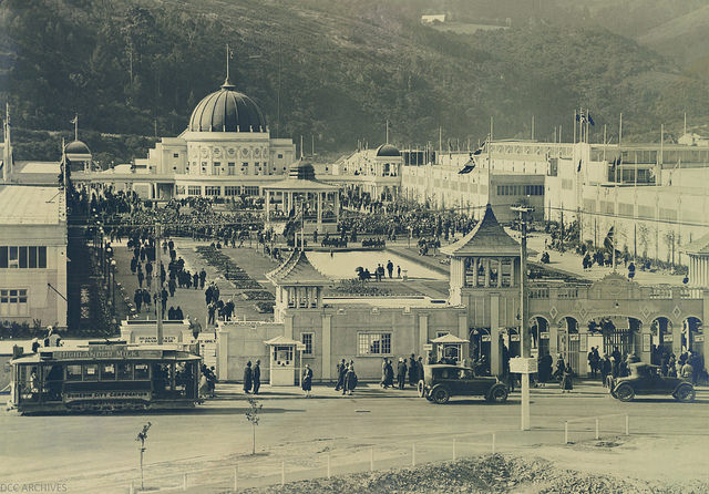 A crowd gathered in an city square with highly decorated buildings on all sides. 