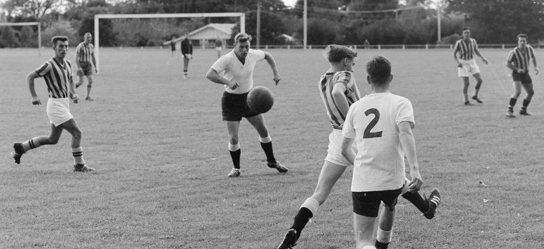 Black and white photograph of a football match in progress on a grass field.