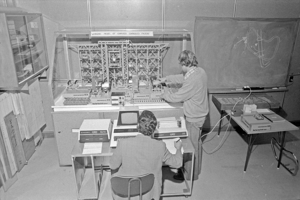 Two men working at a large computer machine.