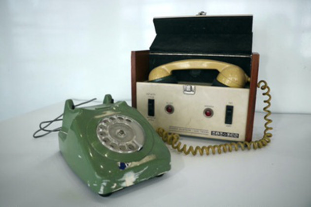 A green dial-up phone with the headset placed in a box with two switches.