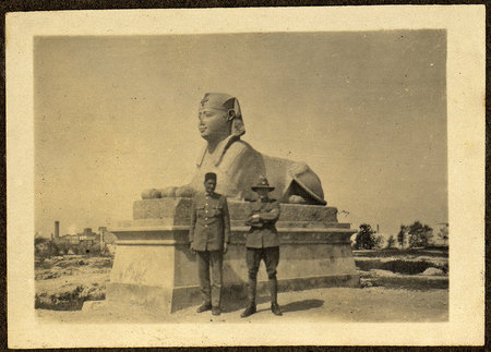 Two men wearing military uniforms standing in front of a sphinx statue.