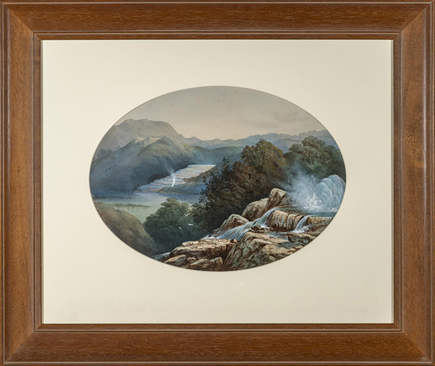 A framed oval painting depicting a dramatic natural landscape with rocky terraces and cascading waterfalls in the foreground, dense green bush, and distant blue mountains and a lake under a soft, cloudy sky.
