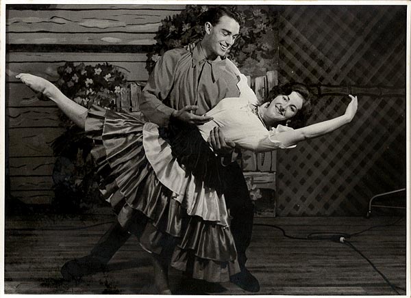 A woman wearing a layered skirt in a dance pose with a man.