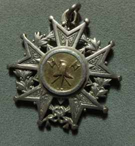 A five reverse-pointed star-shaped medal on a wreath, with a helmet and two axes in the centre.