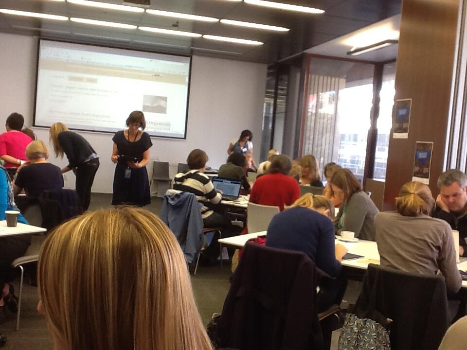 A group of people sitting in a workshop at tables in an office.