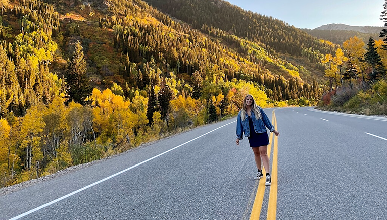 Christina on a yellow line on a road with trees
