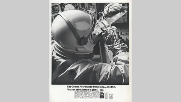 Black and white photo of an astronaut drinking Tang out of a pouch. Picture from 1965
