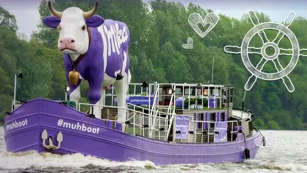 Purple milka boat with giant purple cow on it.