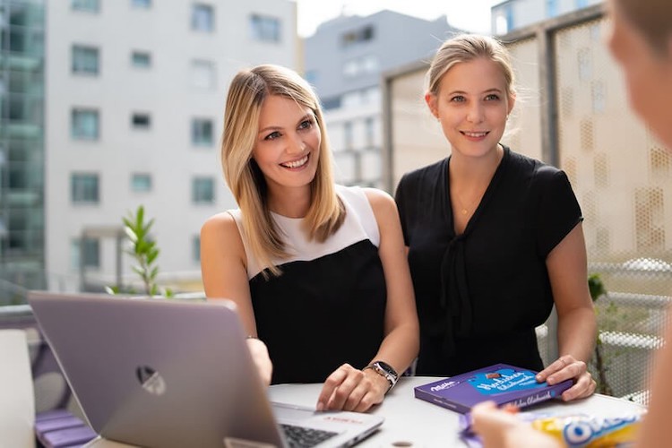 Two ladies smiling in front of a computer