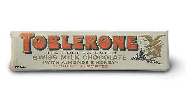 1908 packaging of first Toblerone package. White colour scheme with red Toblerone lettering. Swiss milk chocolate with almonds and honey flavour.
