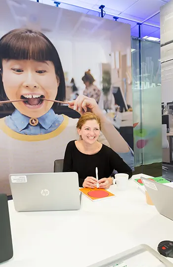 Mondelez Uxbridge employee sittin in front of mural of a person with Mondelez treats