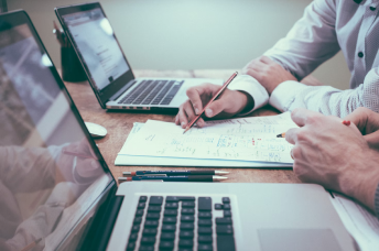 business people pairing on a piece of paper between two computers