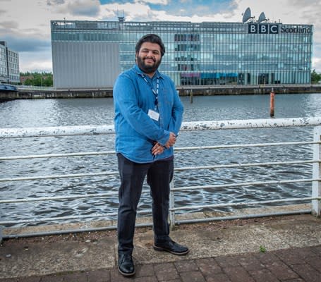 Smiling man outside BBC Scotland building by river