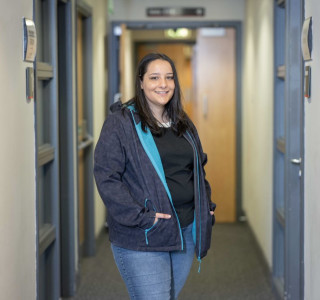 Young woman in a blue jacket  stands in a corridor and smiles to the camera
