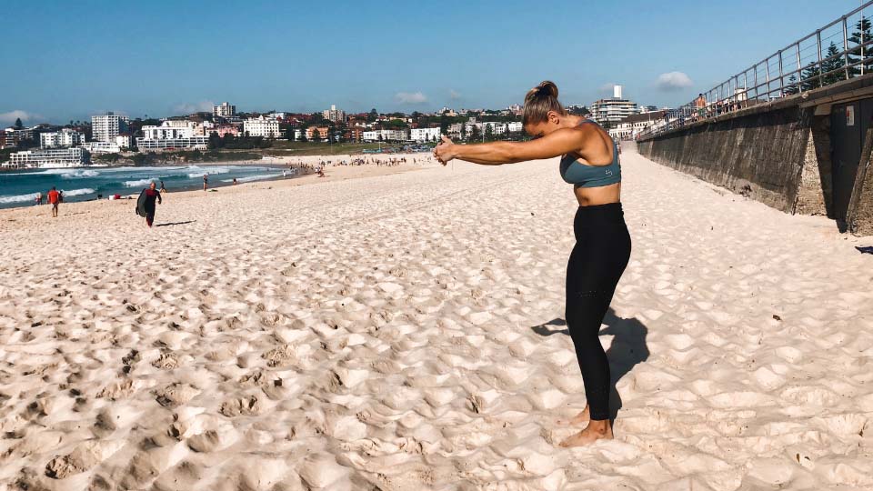 Cassey Maynard stretching her arms out in front of her at the beach.