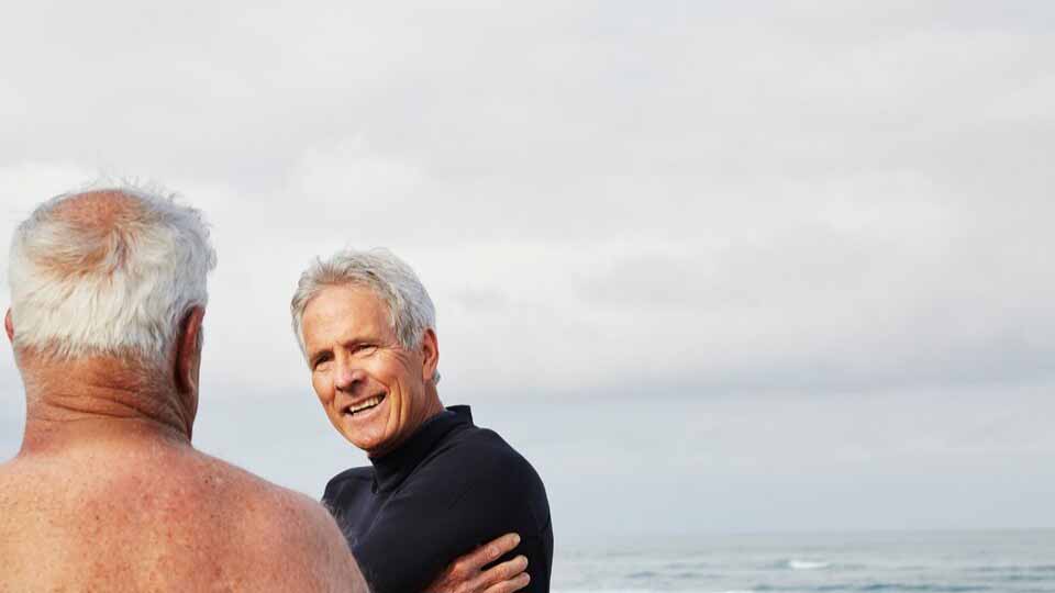 Two men talking by the ocean.