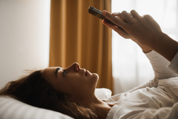 Woman lying in bed with phone