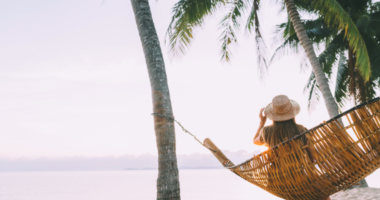 A woman sitting in a hammock on a beach