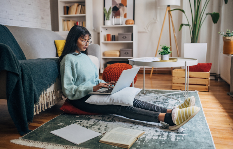 Young female student sitting on the floor with her laptop