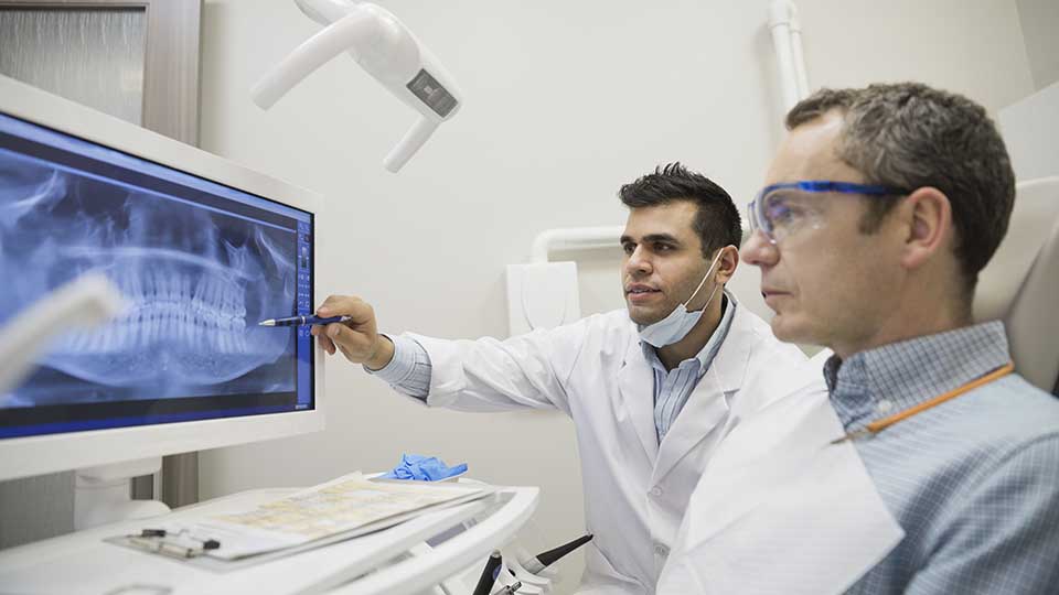 A dentist shows his patient and X-ray of his teeth