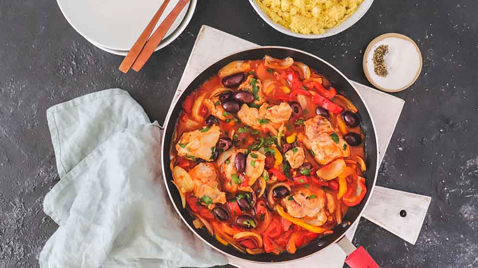 Chicken in tomato sauce with olives in a saucepan.