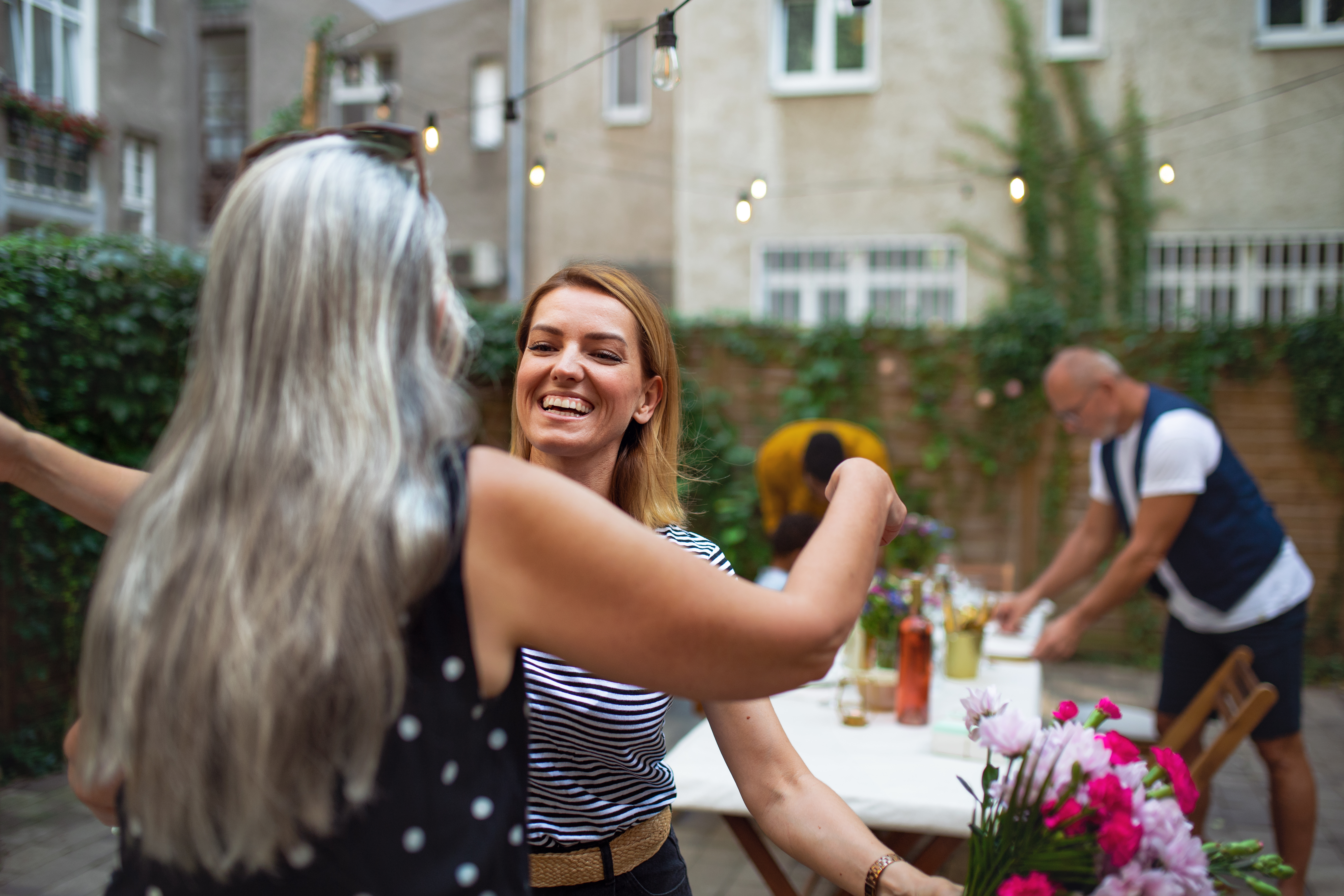 Women smiling and opening her arms for a hug from a friend.