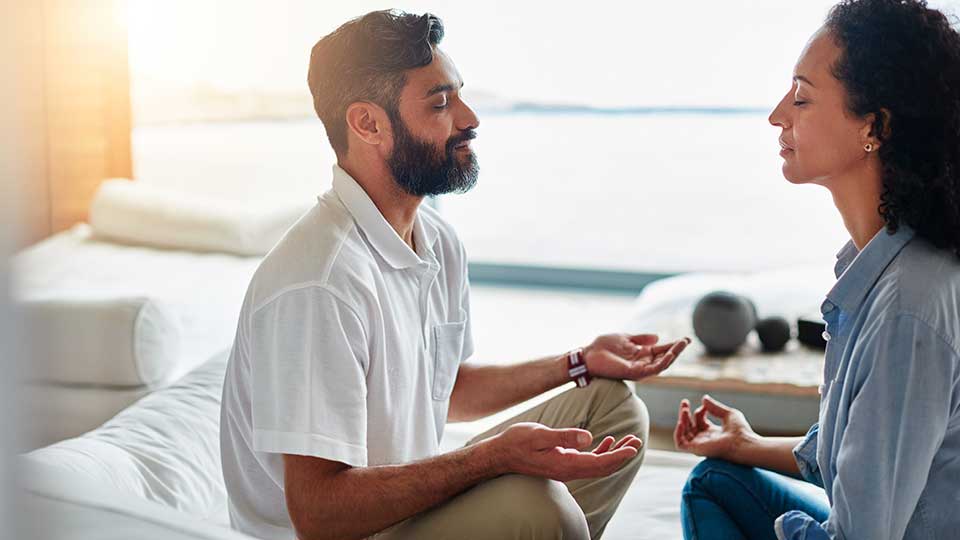 Two middle-aged people meditating in a calming day spa environment.